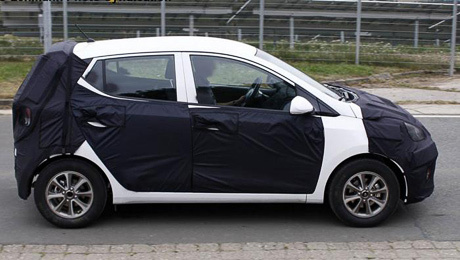 Hyundai i10. Снимки закамуфлированного образца позволяют утверждать, что в размерах новинка изменится не сильно, разве только слегка подрастёт в длину примерно до 3,6-3,65 м.