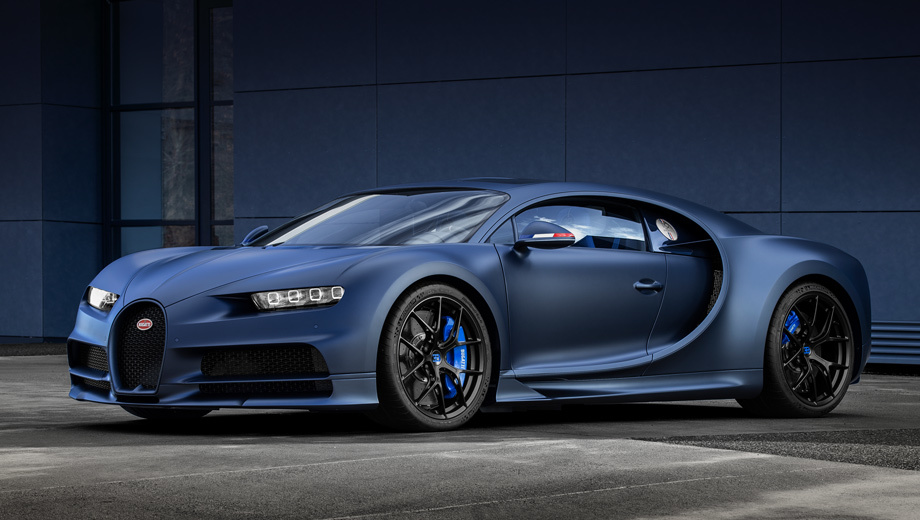 Bugatti chiron. Панели углеволоконного кузова окрашены в матовый колер Steel Blue, напоминающий горячекатаную сталь. Легкосплавные диски снабжены чёрным покрытием Nocturne, за ними видны тормозные суппорты ярко-синего цвета French Racing Blue.